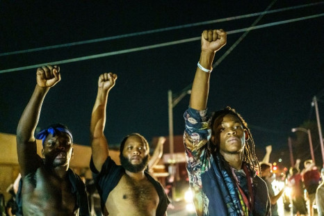Protesters raise their fists during a demonstration against the shooting of Jacob Blake in Kenosha, Wisconsin in a fourth night of protests