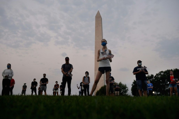 Members of  the Covid Memorial Project hold American flags in front of the Washington monument to commemorate the victims of the coronavirus