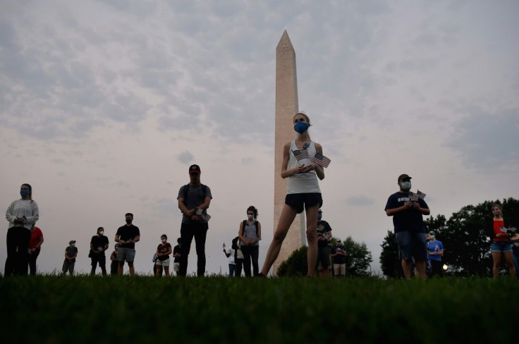 Members of the Covid Memorial Project hold American flags in front of the Washington monument to commemorate the victims of the coronavirus