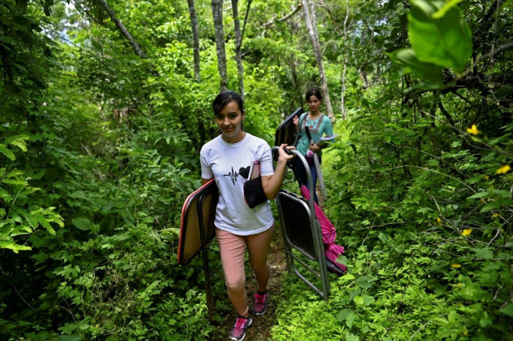 To access their makeshift classroom, the sisters cart a table and chairs one kilometer along a jungle path in search of an internet signal