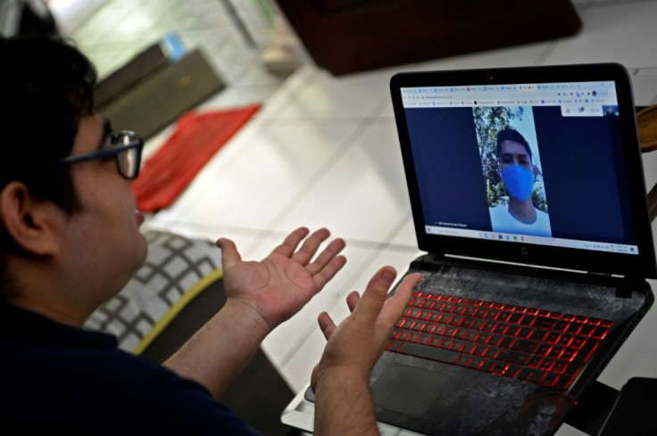 Professor Kevin Salazar communicates online with his student Erick Palacios, who has to climb up a hill to reach internet signal to attend his online university class