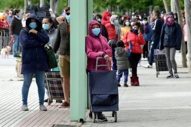 People queue for supplies from a food bank in Madrid on May 16, 2020. In late May, Spain rushed to launch a minimum basic income scheme due to the pandemic which has hit the country hard and devastated the economy