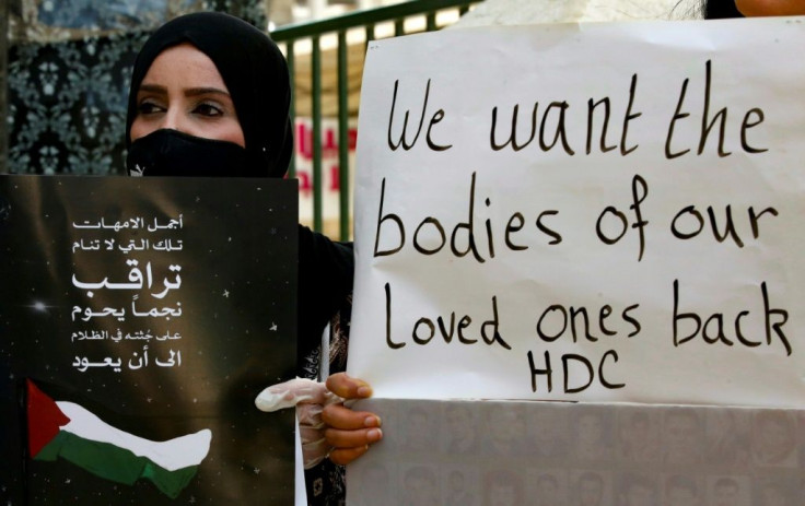 Palestinians hold placards during a demonstration to demand the return of the bodies of relatives who were allegedly involved in attacks and consequently killed by Israeli forces, in the West Bank town of Hebron on Sunday