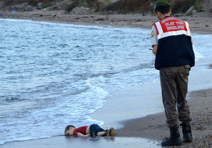A Turkish policeman stands over the body of Aylan, a young migrant, on September 2, 2015. The image brought world attention to the migrants' plight