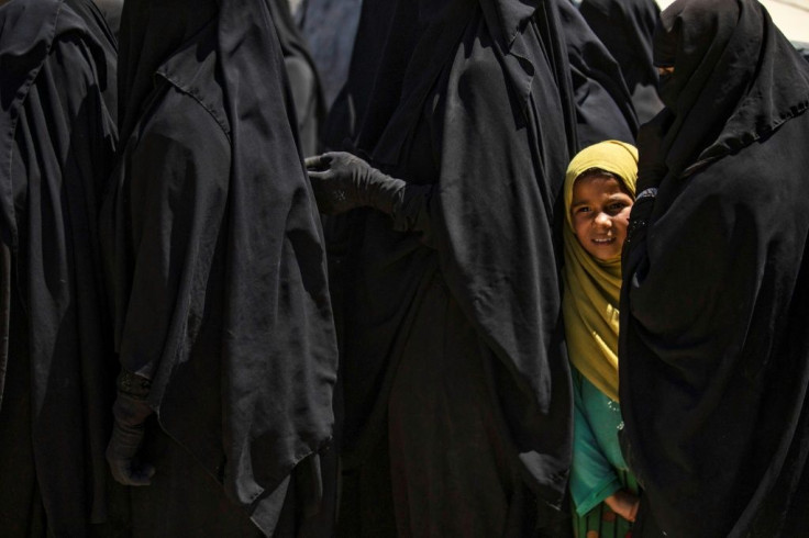 A girl stands in line to receive aid with women at the Kurdish-run al-Hol camp in the al-Hasakeh governorate in northeastern Syria on August 18, 2020, where families of Islamic State (IS) foreign fighters are held.