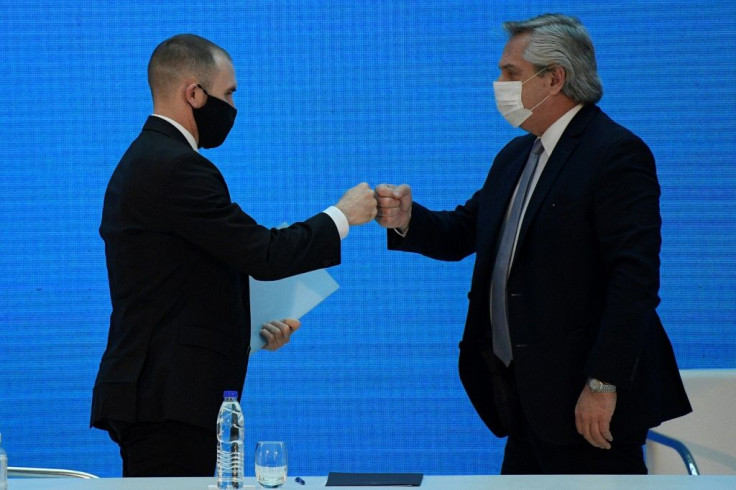 Argentina's President Alberto Fernandez (R) and Economy Minister Martin Guzman greet each other with a fist bump after announcing the restructuring of a $66 billion foreign-law debt