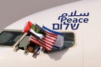 The Emirati, US and Israeli flags fly from the cockpit window of an Israeli El Al aircraft below the word "peace" in Arabic, English and Hebrew, upon its arrival at the Abu Dhabi airport Monday