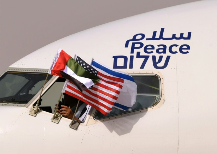 The Emirati, US and Israeli flags fly from the cockpit window of an Israeli El Al aircraft below the word "peace" in Arabic, English and Hebrew, upon its arrival at the Abu Dhabi airport Monday