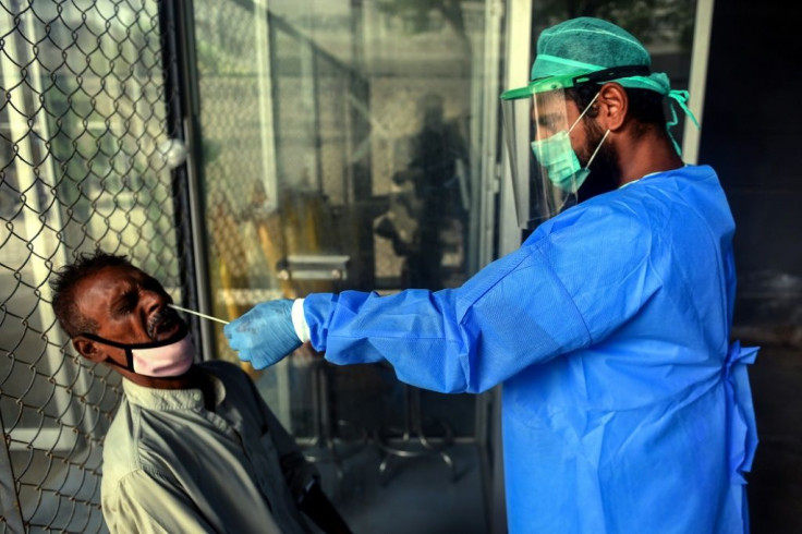 A health official takes a swab sample from a man in Karachi to test for Covid-19