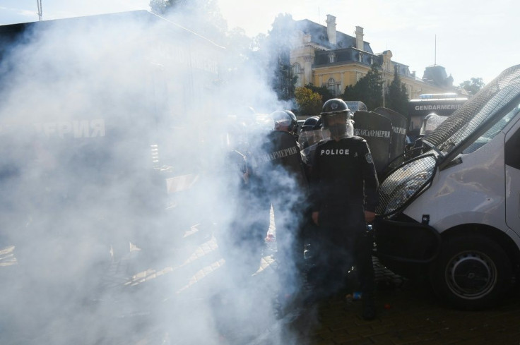 Police officers stand amid tear gas during an anti-government demonstration in Sofia