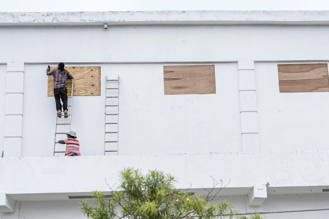 Workers board up the windows of a store in preparation for hurricane Nana in Belize City on Wednesday