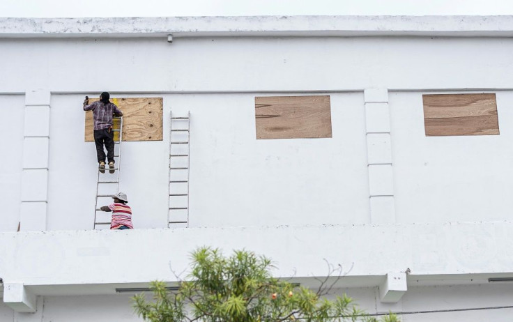 Workers board up the windows of a store in preparation for hurricane Nana in Belize City on Wednesday