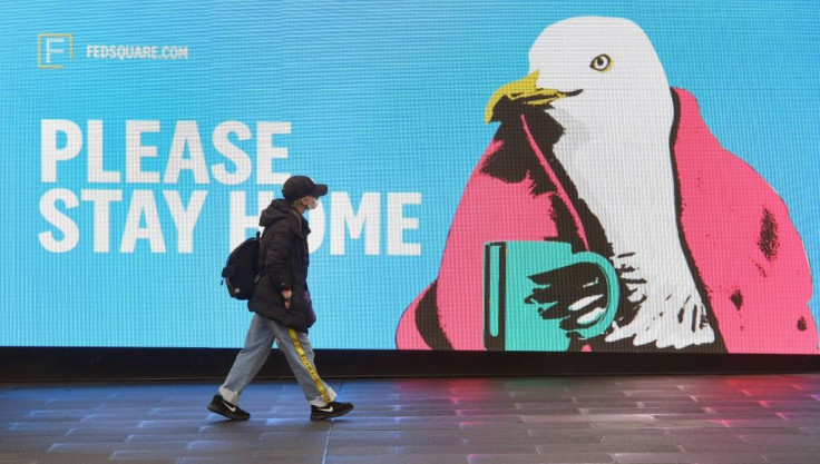 A woman walks past a sign urging people to stay home in Melbourne, which is under lockdown as the city battles an outbreak of the coronavirus