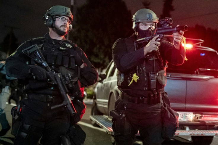 A Multnomah County sheriff's deputy points a weapon at anti-police protesters near the Portland east police precinct a day after violence left one person dead on August 30, 2020 in Portland, Oregon