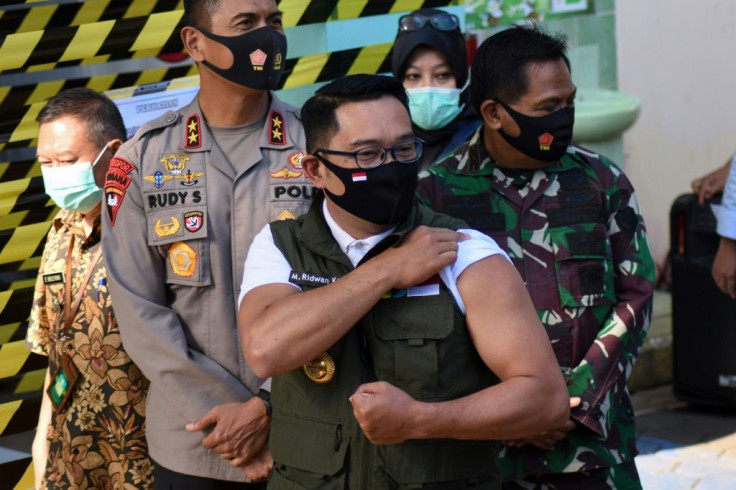 This photo taken on August 28 shows West Java Governor Ridwan Kamil (C) flexing his arm after receving COVID-19 coronavirus vaccine as part of a clinical trial on 1,620 volunteers, at a local health centre in Bandung, West Java.