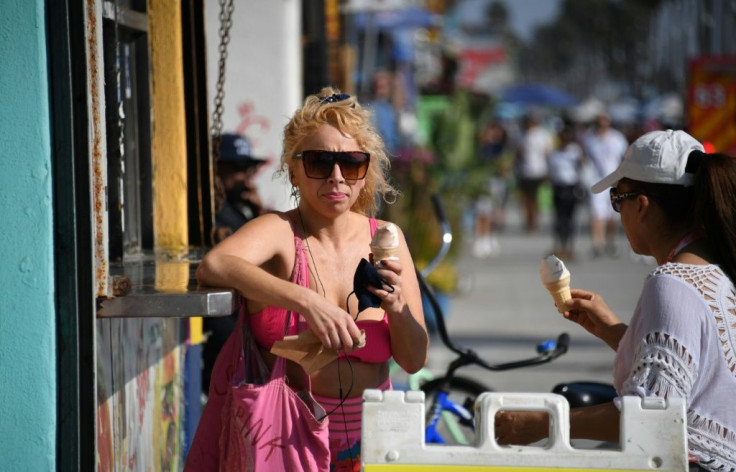 A woman enjoys an ice cream as people come to the beach to escape the heat wave in Venice Beach, California on September 4, 2020.