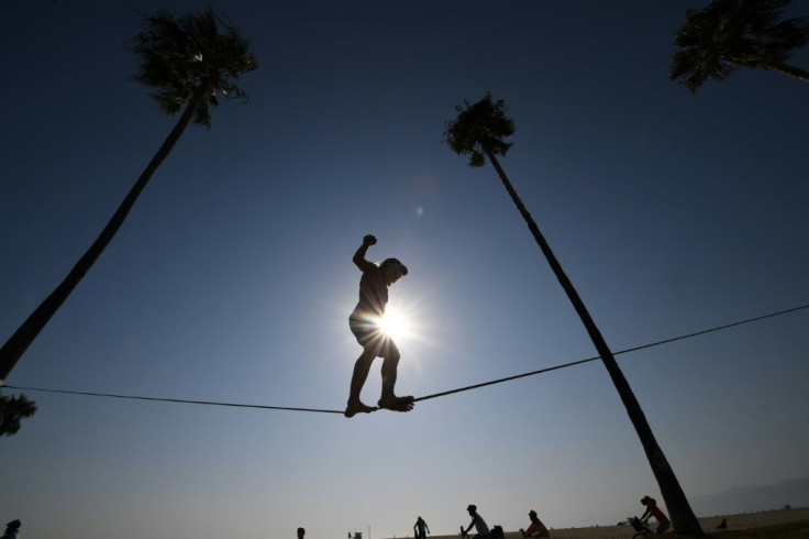Chuck Reynolds practices his skill on a slack rope in Venice Beach where people flock to the ocean to escape the heat wave on September 4, 2020