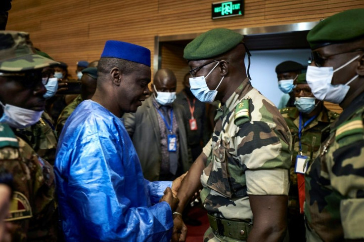 Junta number two Malick Diaw, right, shakes hands with Issa Kaou Djim, a leading figure in the June 5 Movement as talks began