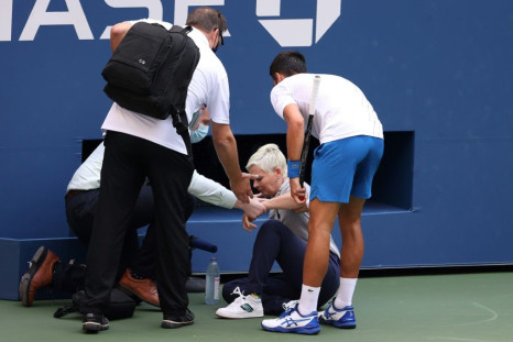 Novak Djokovic of Serbia tends to a lineswoman after inadvertently striking her with a ball hit in frustration during his Men's Singles fourth round match against Pablo Carreno Busta of Spain on Day Seven of the 2020 US Open at the USTA Billie Jean King N
