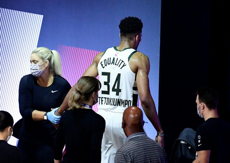 Milawukee star Giannis Antetokounmpo gingerly leaves the court after re-injuring his right ankle in the first half of the Bucks' must-win NBA playoff series game four against the Miami Heat