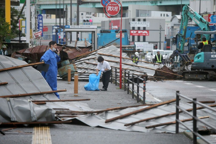 A clean-up crew works to remove roofs that  were blown off into a Fukuoka street by Typhoon Haishen
