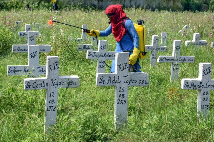 A worker sanitises a Roman Catholic Church graveyard after the burial of Covid-19 patients in the Indian city of Ranchi