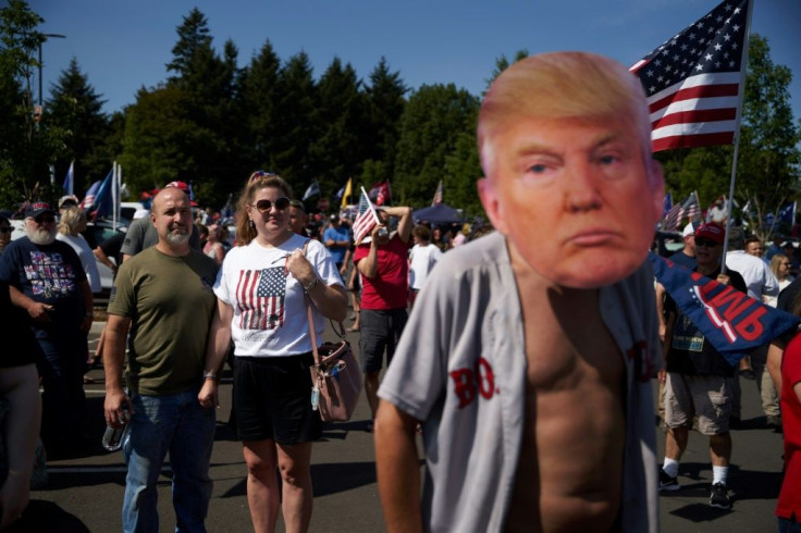 A fan wears a mask depicting President Donald Trump, who is traveling the country to whip up support as polls show him down eight weeks before election day