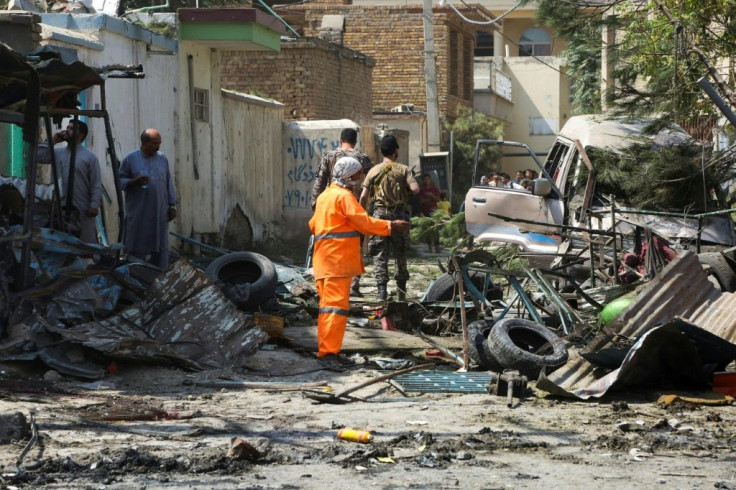 Afghan security personnel inspect the site of an explosion targeting Amrullah Saleh's convoy