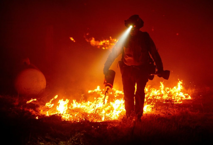 Firefighters cut defensive lines and light backfires to protect structures behind a CalFire fire station during the Bear fire