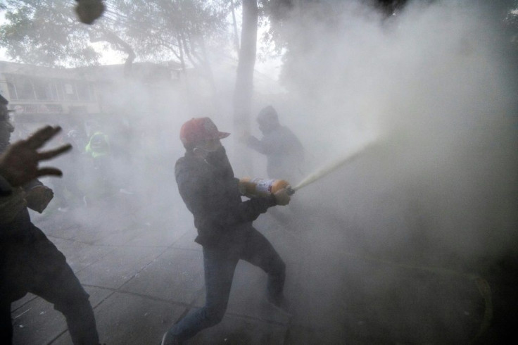 A protester sprays foam from a fire extinguisher during a protest in Bogota against police brutality