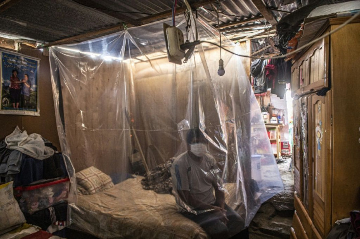 Jonathan, 30, sits on his bed behind a plastic protection as doctors make a round of visits in Ate, on the eastern outskirts of Lima