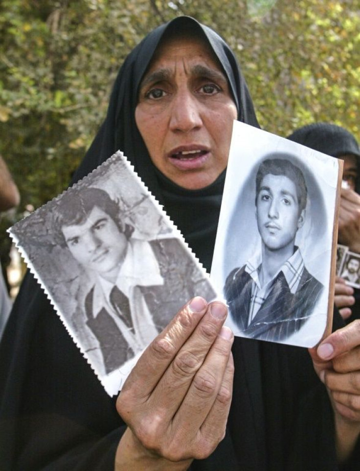 An Iraqi woman shows in this May 2003 picture photographs of her two sons who were believed to have been killed during Saddam's rule