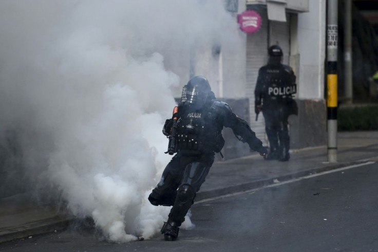 A riot police officer kicks a tear gas canister during protests against police brutality in Medellin, Colombia