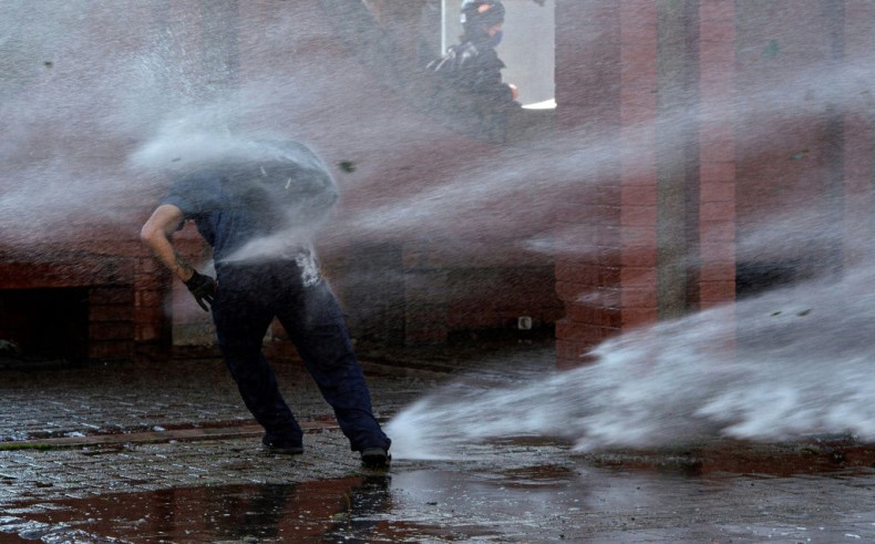 A demonstrator is hit by a jet from a water cannon during a protest in homage to the victims of Chile's 1973 military coup, in Santiago, September 2020