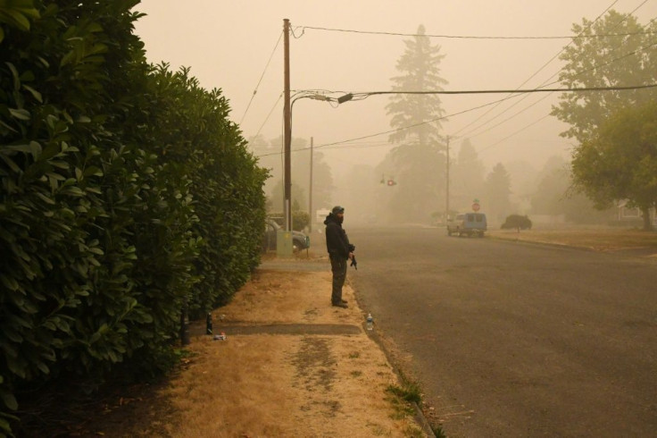 A man stands guard with a firearm outside his home after wildfires and heavy smoke caused many of his neighbors to evacuate the area, in Estacada, Oregon on September 12, 2020