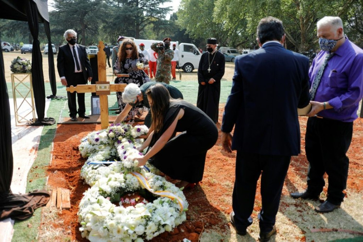 Mourners shovel sand into the grave of Bizos
