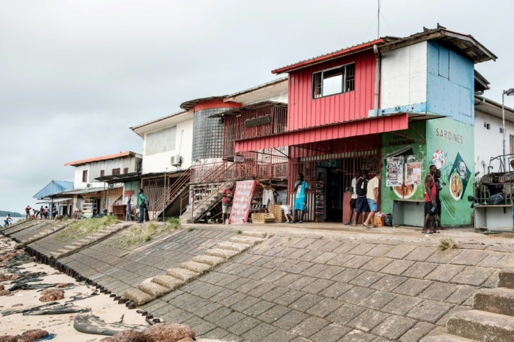 People stand by shops usually run by Chinese citizens in Albina, Suriname in January 2019 amid a rise in investment by China