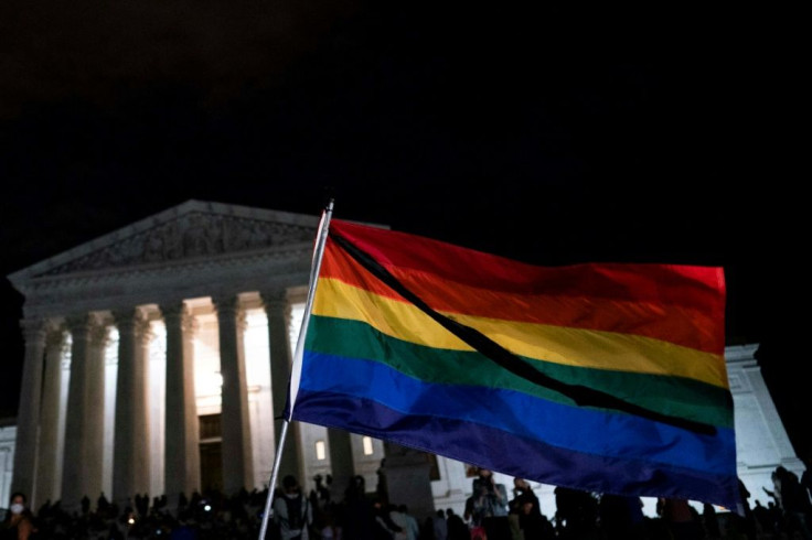 A rainbow flag waves as people gather near the steps of the Supreme Court buidling to pay tribute to Ruth Bader Ginsburg, who was known for her role in wideining LGBTQ rights