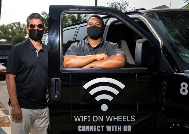 Roman Reyna (L) and Kevin Watson (R), of  JFK Transportation, pose by one of their minivans that give underserved kids wifi access in Santa Ana, California
