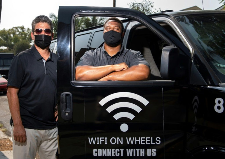 Roman Reyna (L) and Kevin Watson (R), of JFK Transportation, pose by one of their minivans that give underserved kids wifi access in Santa Ana, California