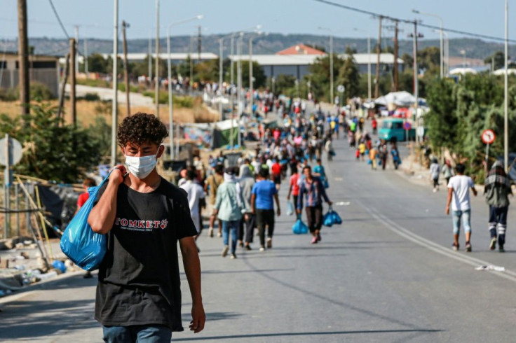 Migrants walk near the temporary camp during a police operation to rehouse thousands