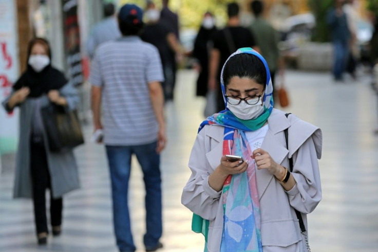Shoppers, wearing protective masks due to the Covid-19 pandemic, walk past shops in Vali-asr Square in the Iranian capital Tehran on September 20, 2020