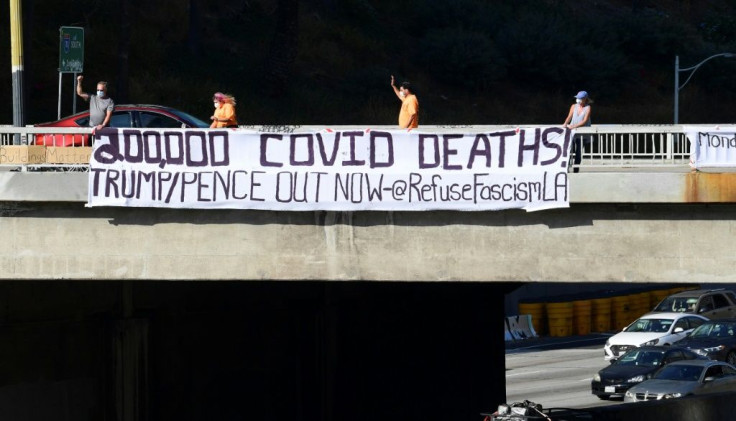 Activists unfurl a banner reading "200,000 Covid Deaths! Trump/Pence Out Now" over a freeway in  Los Angeles
