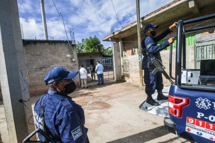 Armed police accompany the health workers as they visit homes
