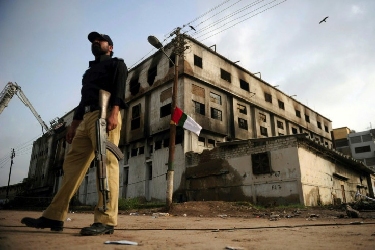A Pakistani policeman stands guard in 2012 outside the burnt-out Ali Enterprises garment factory in Karachi