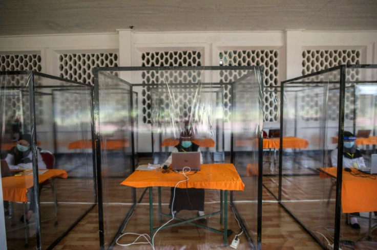 Candidates for Indonesian civil servant jobs sit an exam inside a plastic chamber after they tested positive for COVID-19