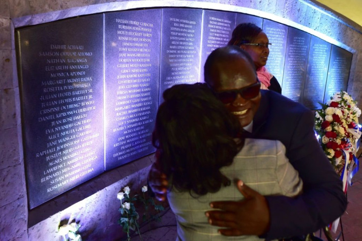 Survivors of the 1998 bombing of the US embassy in Nairobi embrace in 2018 as they stand beside a plaque bearing the names of those killed