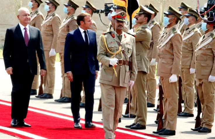 Iraq's President Barham Saleh, who is warning of risks to his country, inspects an honor guard as he welcomes French President Emmanuel Macron (left) on September 2, 2020