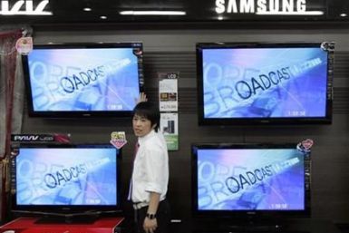 An electronics shop salesperson sells flat screen TVs of Samsung Electronics displayed at a shop in Seoul