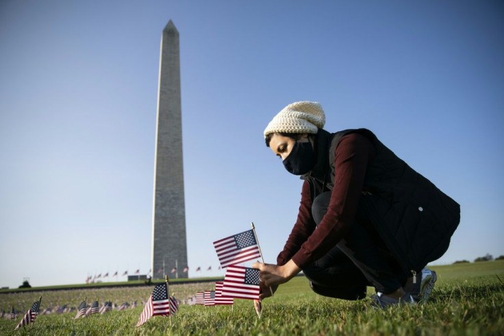 A woman places a flag at a memorial on the National Mall in Washington fo the more than 200,000 people in the United States who have died of Covid-19